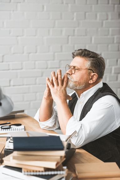 thoughtful-senior-man-sitting-at-work-desk-with-st-2024-11-19-02-46-13-utc